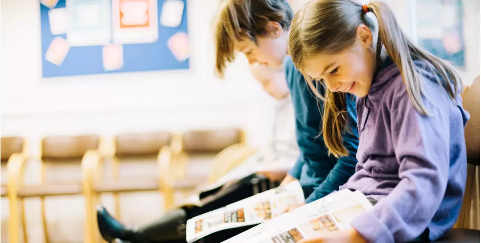 Une fille et un garçon qui lisent un journal